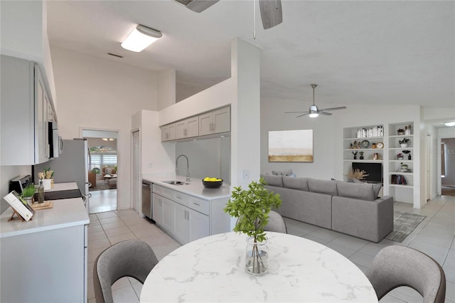 dining space featuring ceiling fan, light tile patterned floors, lofted ceiling, and sink