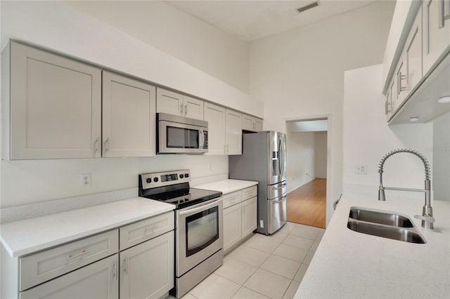 kitchen featuring gray cabinets, appliances with stainless steel finishes, light tile patterned flooring, and sink