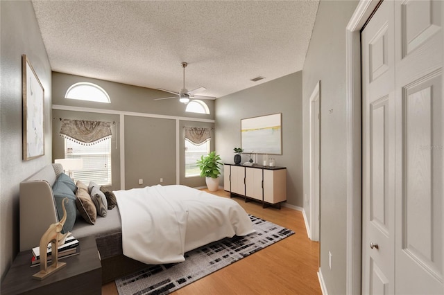 bedroom featuring light hardwood / wood-style floors, ceiling fan, and a textured ceiling