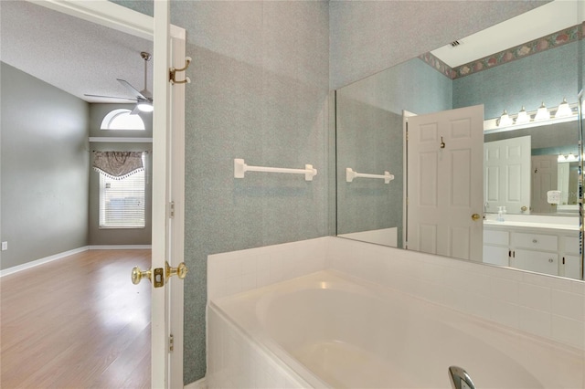 bathroom featuring a textured ceiling, hardwood / wood-style flooring, a washtub, ceiling fan, and vanity