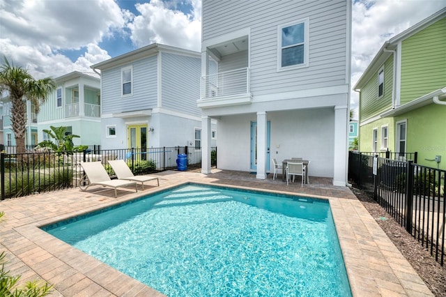 rear view of property featuring a patio area, a fenced in pool, and a balcony