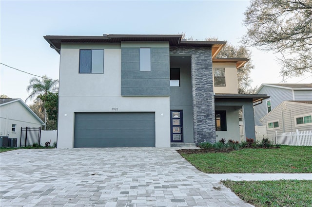 modern home with a garage, central AC, and a front yard