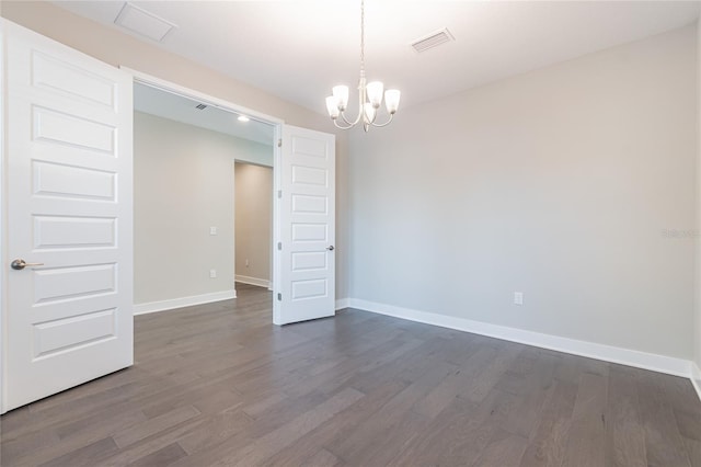 empty room featuring dark wood-type flooring, visible vents, a notable chandelier, and baseboards