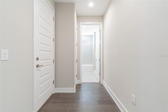 hallway featuring dark wood-type flooring and baseboards