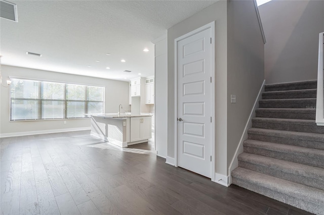 staircase with visible vents, a textured ceiling, baseboards, and wood finished floors