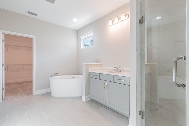 full bathroom featuring a walk in closet, visible vents, a shower stall, a freestanding tub, and baseboards