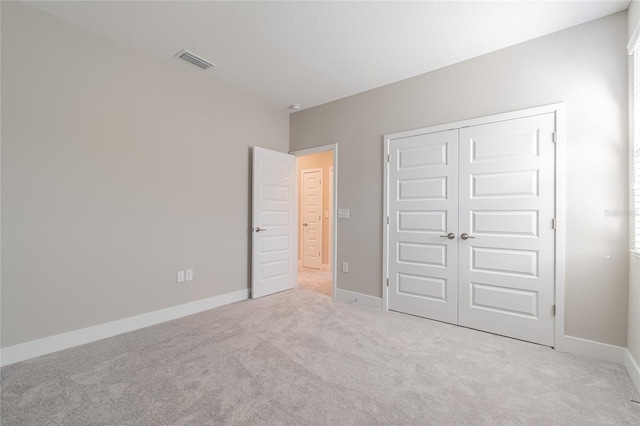 unfurnished bedroom featuring carpet floors, a closet, visible vents, and baseboards