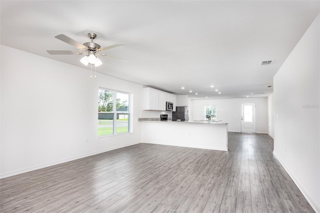 unfurnished living room featuring light hardwood / wood-style floors, ceiling fan, and a healthy amount of sunlight