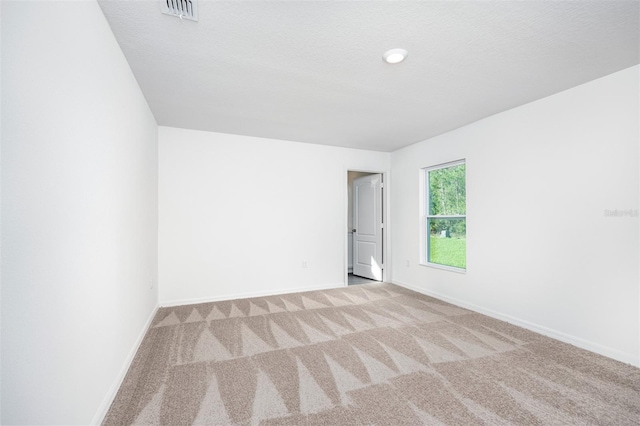 unfurnished room with a textured ceiling and light carpet