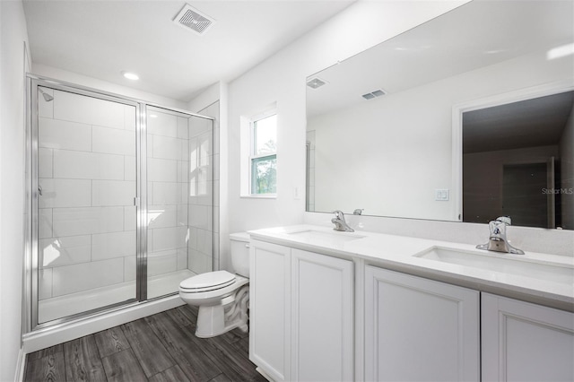 bathroom with hardwood / wood-style flooring, vanity, toilet, and a shower with shower door