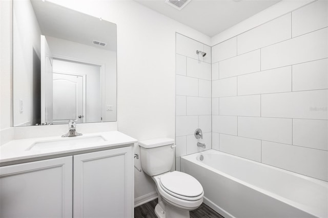 full bathroom featuring hardwood / wood-style flooring, vanity, tiled shower / bath combo, and toilet