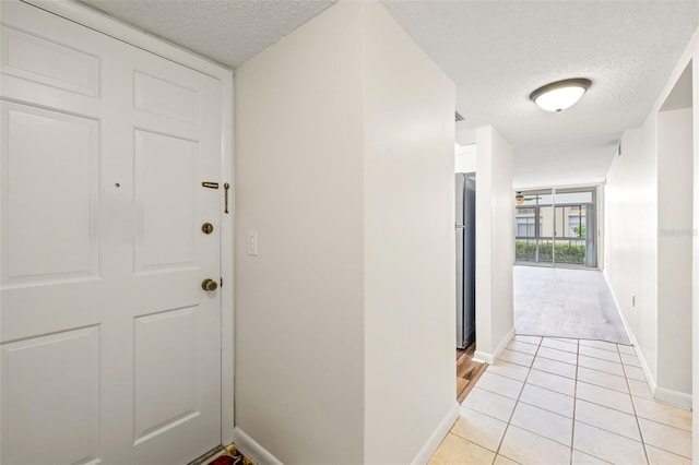 hall featuring light tile patterned floors and a textured ceiling