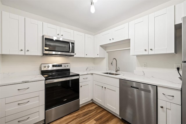 kitchen featuring light stone countertops, sink, dark hardwood / wood-style floors, white cabinets, and appliances with stainless steel finishes