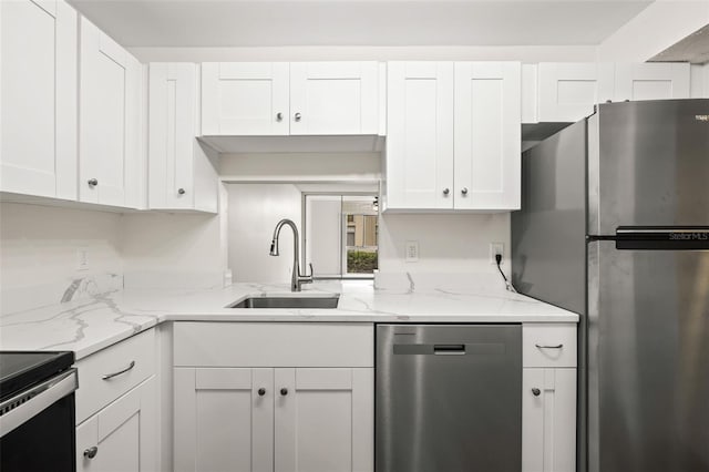 kitchen with white cabinets, sink, light stone countertops, and stainless steel appliances