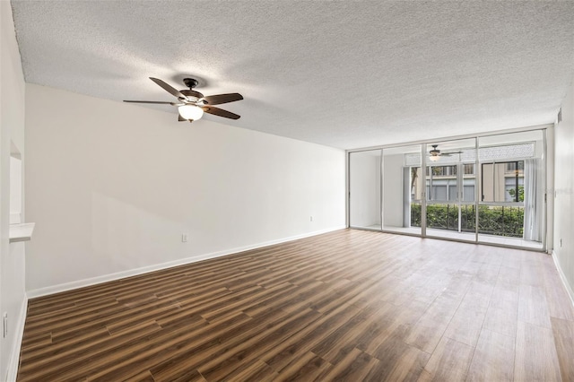 empty room featuring floor to ceiling windows, a textured ceiling, and dark wood-type flooring