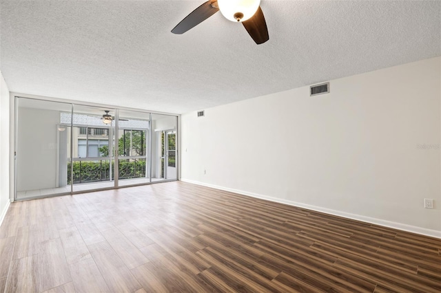 spare room featuring ceiling fan, dark hardwood / wood-style flooring, a textured ceiling, and a wall of windows