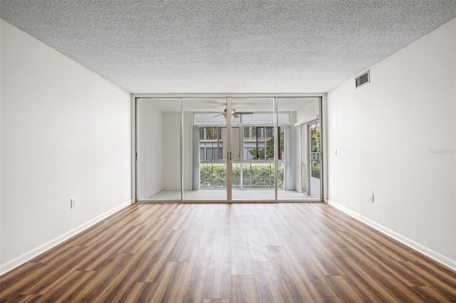 spare room with ceiling fan, floor to ceiling windows, dark hardwood / wood-style floors, and a wealth of natural light