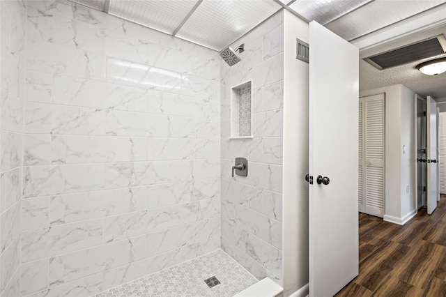 bathroom with tiled shower and wood-type flooring