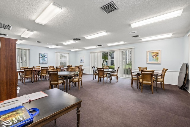 carpeted dining space featuring a textured ceiling