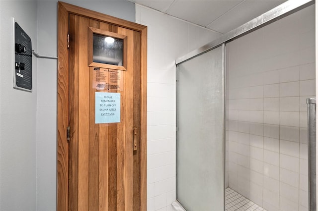 bathroom featuring wooden walls and a shower with door