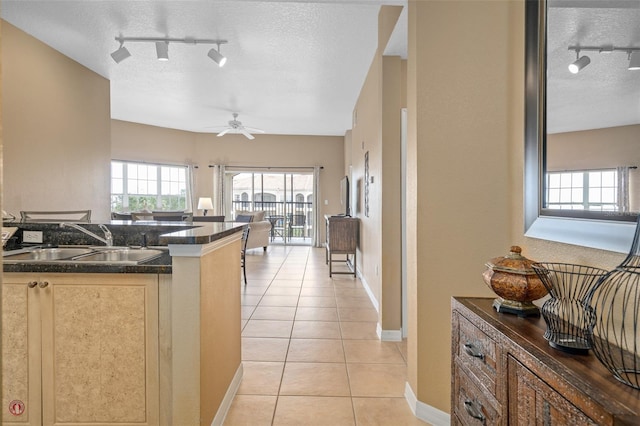 kitchen featuring light tile patterned flooring, track lighting, ceiling fan, and sink