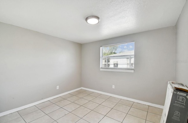 tiled empty room featuring a textured ceiling