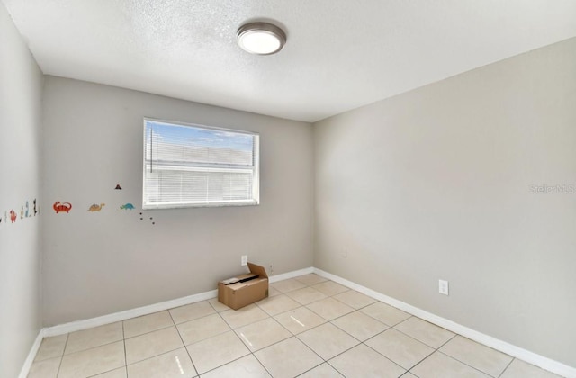 tiled spare room featuring a textured ceiling