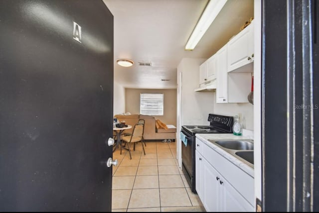 kitchen featuring black / electric stove, white cabinetry, sink, and light tile patterned floors