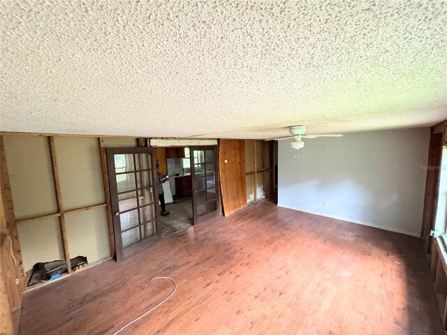 interior space with ceiling fan, a textured ceiling, and hardwood / wood-style flooring