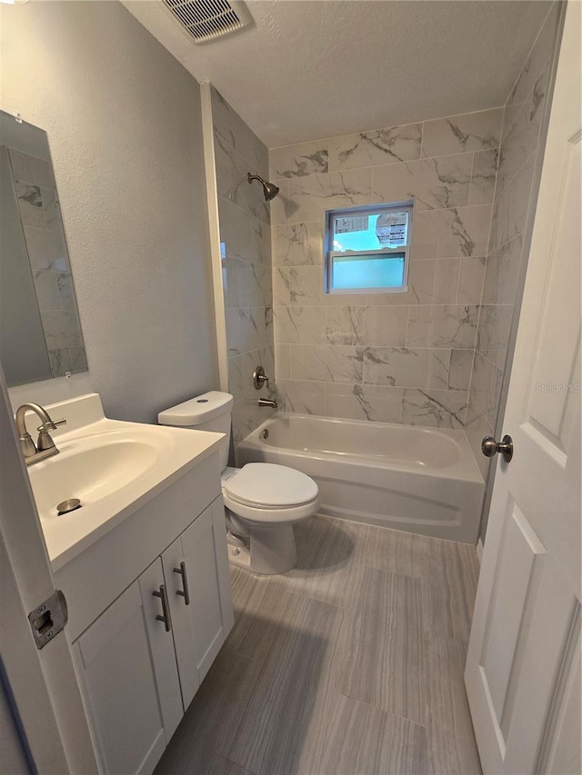 full bathroom with toilet, tiled shower / bath, wood-type flooring, a textured ceiling, and vanity