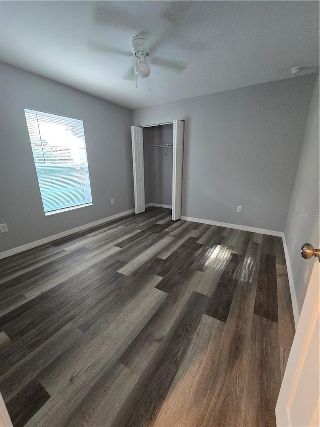 unfurnished bedroom featuring dark hardwood / wood-style floors, ceiling fan, and a closet