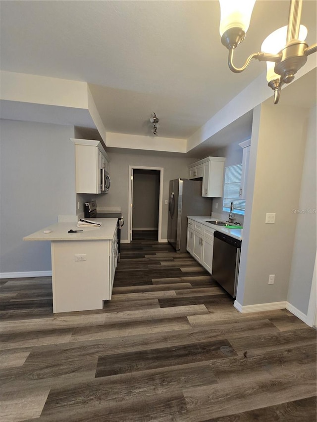 kitchen with sink, appliances with stainless steel finishes, white cabinetry, dark hardwood / wood-style floors, and kitchen peninsula