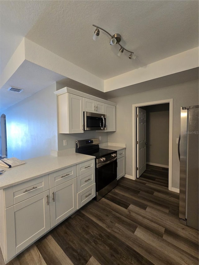 kitchen featuring stainless steel appliances, white cabinetry, dark wood-type flooring, and a textured ceiling