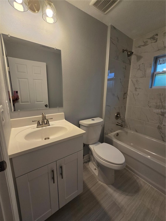 full bathroom featuring tiled shower / bath, vanity, and toilet