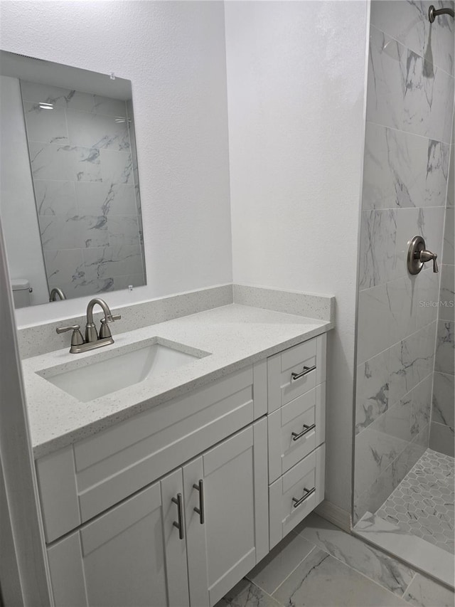 full bath featuring marble finish floor, toilet, vanity, and tiled shower
