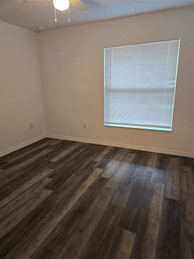 unfurnished room with a ceiling fan, baseboards, and dark wood-style flooring