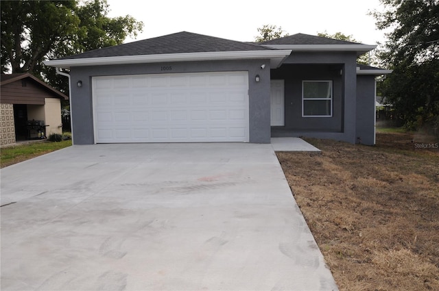 ranch-style house with stucco siding, an attached garage, driveway, and roof with shingles