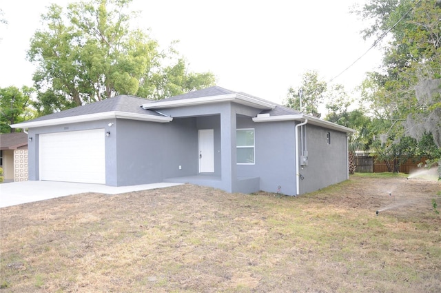 view of front facade with stucco siding, driveway, a front yard, and a garage