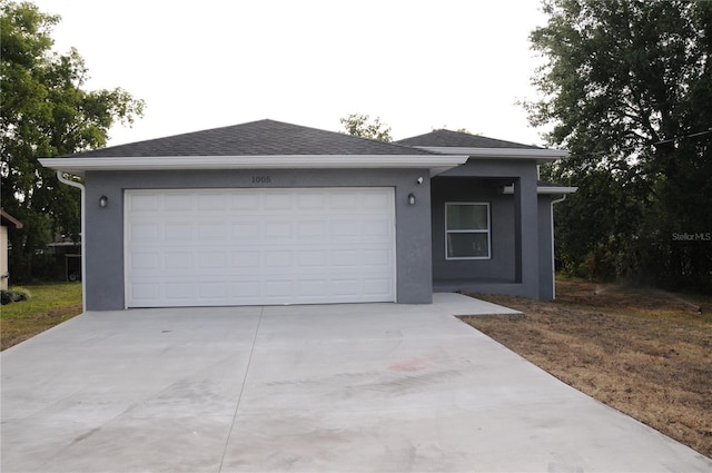 ranch-style home featuring an attached garage, a shingled roof, driveway, and stucco siding