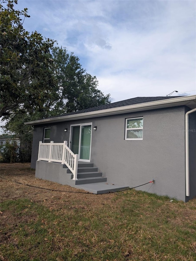 exterior space featuring stucco siding and a front yard