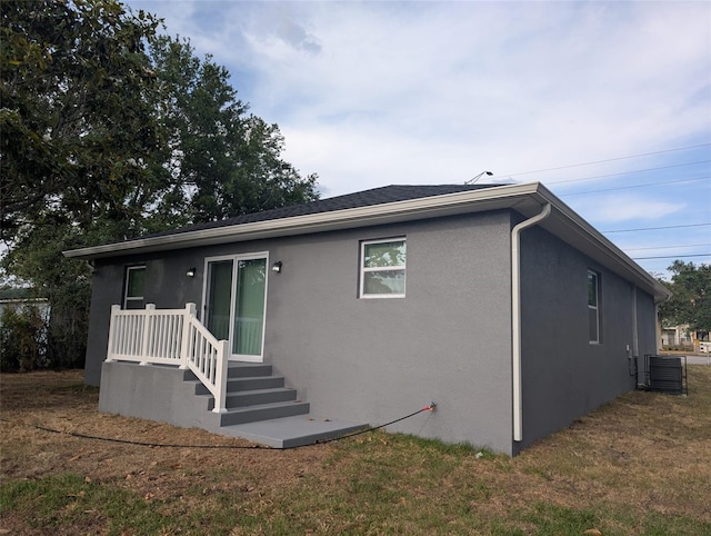 exterior space with central air condition unit, a front lawn, and stucco siding