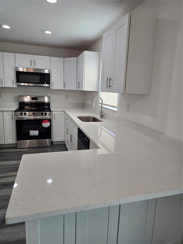 kitchen featuring light stone counters, a sink, white cabinetry, appliances with stainless steel finishes, and recessed lighting