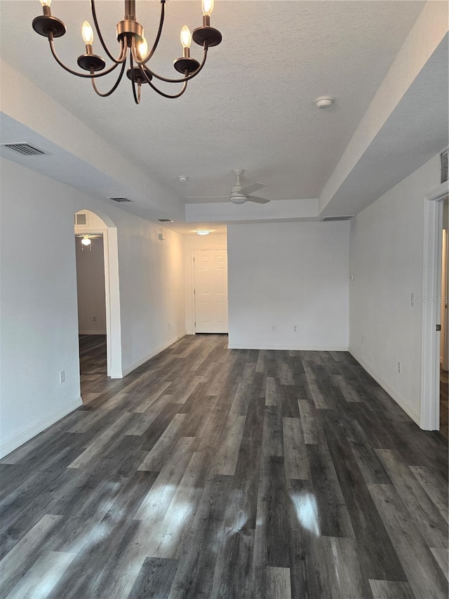 unfurnished living room with dark wood finished floors, visible vents, arched walkways, baseboards, and ceiling fan with notable chandelier