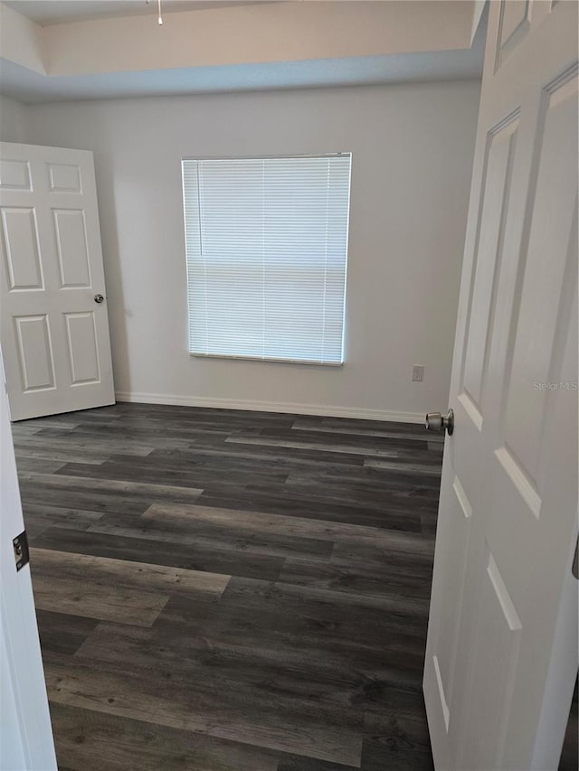 empty room featuring baseboards and dark wood-style floors