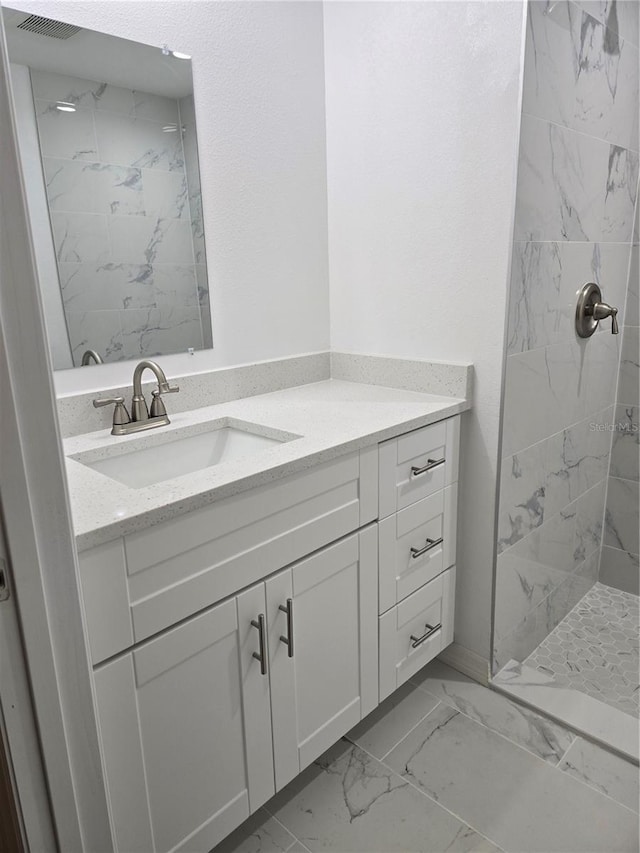 bathroom featuring visible vents, marble finish floor, vanity, and tiled shower