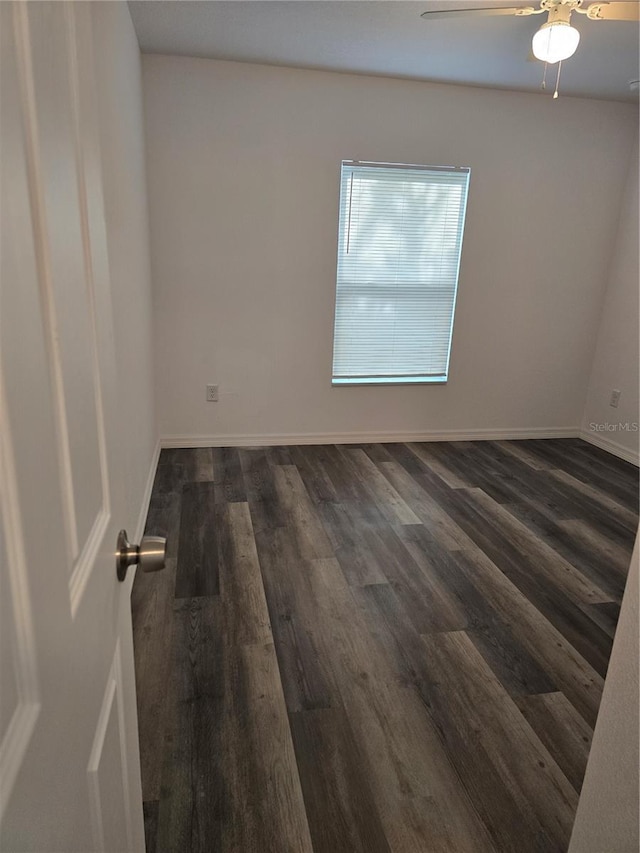 spare room featuring baseboards, a ceiling fan, and dark wood-style floors