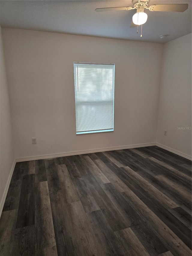 unfurnished room with baseboards, a ceiling fan, and dark wood-style floors