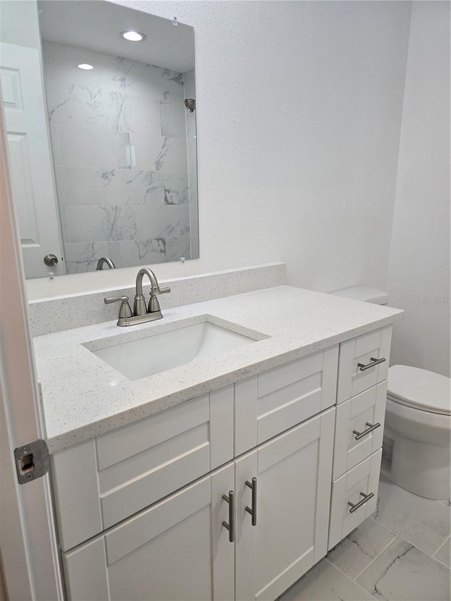 bathroom with marble finish floor, a tile shower, toilet, and vanity