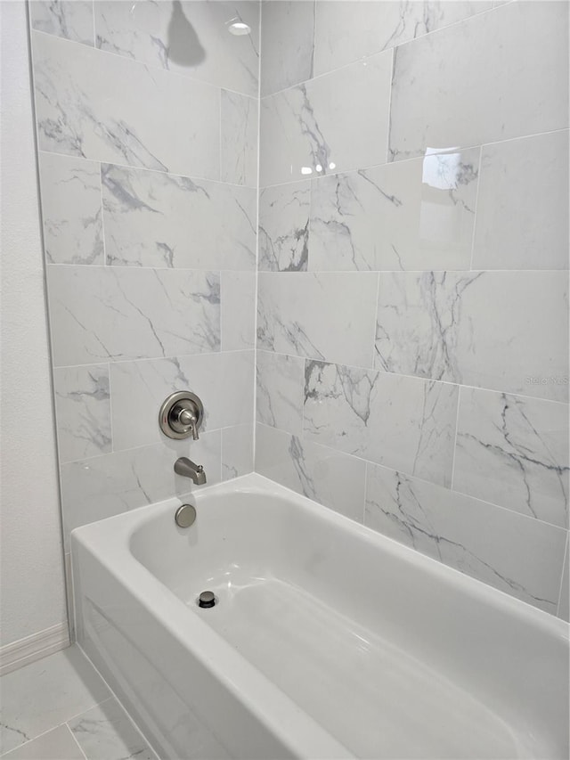 bathroom featuring marble finish floor, shower / bath combination, and baseboards
