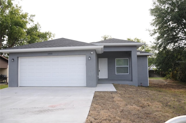 ranch-style home featuring stucco siding, an attached garage, and concrete driveway